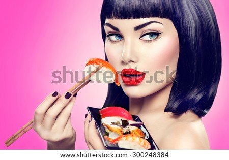 Beauty Fashion model girl eating Nigiri Sushi with chopsticks. Beautiful sexy woman with perfect make up and bob haircut eating healthy japanese food. Diet, dieting concept.