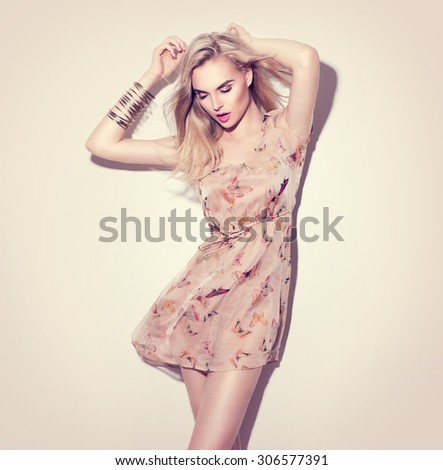Fashion model Girl portrait dressed in short chiffon beige dress. Blowing blonde hair