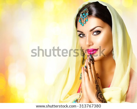 Beauty Indian woman  portrait. Hindu girl hold hands together is symbol prayer and gratitude. Indian model girl with black henna tattoos looking in camera. Mehndi. Indian marriage traditions