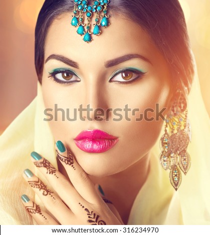 Beauty brunette Indian woman portrait. Hindu model girl with brown eyes, mehndi tattoo on hand and national Indian jewels looking in camera. Indian girl in sari. Marriage Traditions. Indian culture