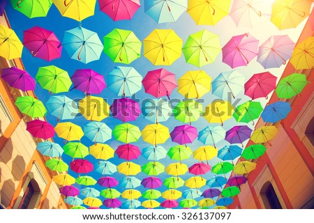 Colorful umbrellas background. Colourful umbrellas urban street decoration. Hanging Multicoloured umbrellas over blue sky. Bright Colors backdrop