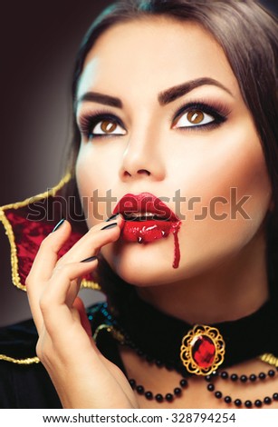 Beautiful Halloween Vampire Woman portrait. Beauty Sexy Vampire lady with blood on her mouth. Fashion Art design. Attractive model girl in Halloween costume and make up