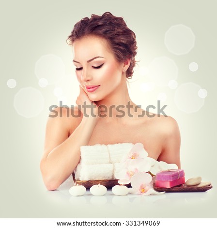 Beauty Spa Woman touching her soft skin, Beautiful girl portrait. Day spa, wellbeing concept. Handmade soap bars, towels, candles and orchid flowers on her table