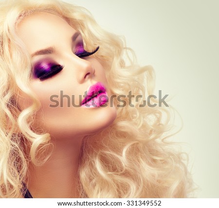 Beauty Girl With Healthy Long Curly Hair. Blonde Woman Portrait. Blond Wavy Hair and bright makeup, vivid make-up, purple lips, smoky eyes and false eyelashes. Holiday make up. Perfect skin