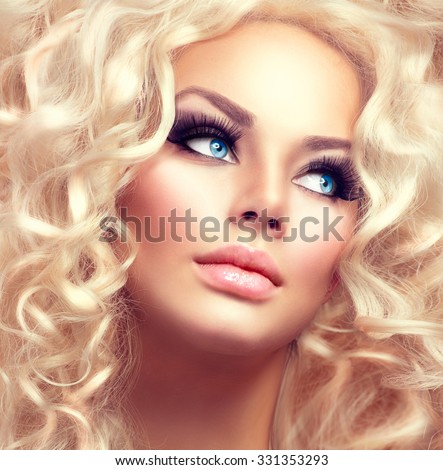 Beauty Girl With Healthy Long Curly Hair. Blonde Woman Portrait with blue eyes. Blond Wavy permed Hair and bright makeup, vivid make-up, smoky eyes and false eyelashes. Holiday make up. Perfect skin