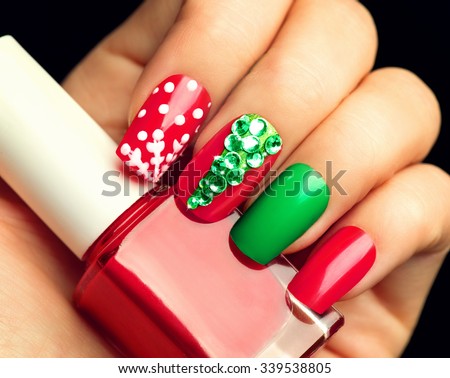 Christmas Nail art manicure. Winter Holiday style bright Manicure with gems Christmas tree and snowflakes. Bottle of Nail Polish. Beauty hands. Trendy Stylish Colorful Nails, Nailpolish