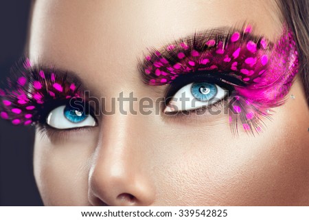 Creative Holiday Makeup. False long purple eyelashes closeup. Beauty model woman face make-up with fantasy bright eyelash