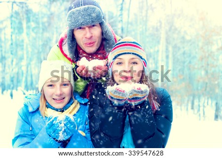 Winter Family Outdoors. Happy Joyful Family with kid blowing Snow. Wintertime, winter fun