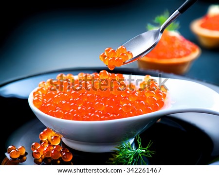 Caviar. Red caviar in spoon on a black background. Gourmet food. Gourmet food close up, appetizer