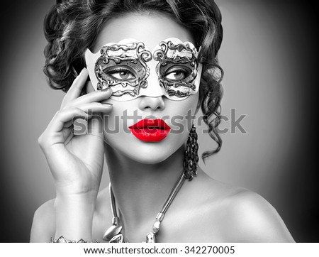 Beauty model woman wearing venetian masquerade carnival mask at party. Christmas and New Year celebration. Sexy girl with holiday makeup.Black and white portrait with Red lips
