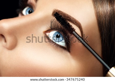 Mascara applying closeup, long lashes. Mascara brush. Eyelashes extensions. Make-up for blue eyes. Eye make up apply