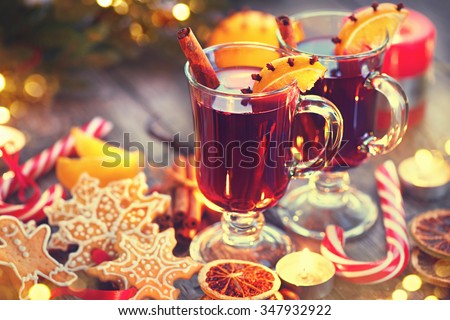 Traditional Christmas Mulled Wine hot drink with cinnamon stick, slices of orange and spices, on holiday decorated Christmas table. Christmas dinner