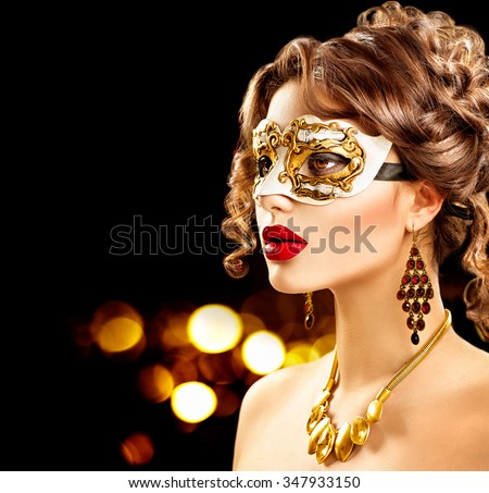 Beauty model woman wearing venetian masquerade carnival mask at party over holiday dark background with magic glow. Christmas and New Year celebration. Glamour lady with perfect make up and hairstyle