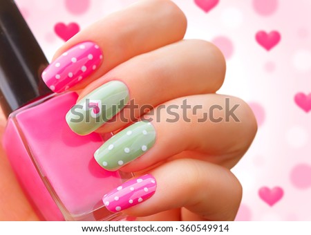 Valentine Nail art manicure. Valentine\'s Day Holiday style bright Manicure with painted hearts and polka dots. Bottle of Nail Polish. Beauty salon. Hand. Trendy Stylish Colorful Nails, Nailpolish