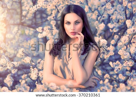 Spring fashion girl outdoors portrait in blooming trees. Beauty Romantic woman in flowers. Sensual Lady. Beautiful Woman Enjoying Nature. Romantic beauty in fantasy orchard