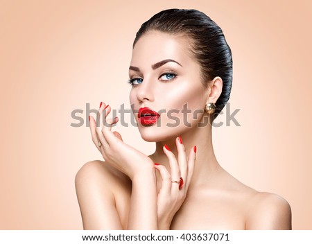 Beauty Fashion Model Woman face. Portrait with perfect skin. Red Lips and Nails. Beautiful Sexy Brunette Woman with Luxury Makeup and Manicure over beige background