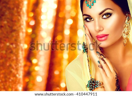 Beautiful Arabic girl portrait. Beauty young Arabian woman with menhdi, perfect make-up and accessories hiding her face behind a veil. Indian Bride. Arab Traditions and culture concept