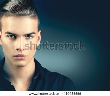 High Fashion model man portrait isolated on dark background. Handsome guy closeup. Stylish haircut, hairstyle. Hair style. Vogue style image of elegant boy