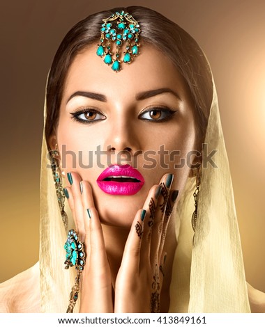 Beauty Indian woman portrait. Brunette Hindu model girl with brown eyes, mehndi or mehendi tattoo on her hand and national Indian jewels looking in camera. Indian girl in sari.