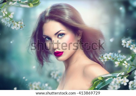Fashion Spring Model Girl Portrait with Long Blowing Hair. Sexy Glamour Summer Beautiful Woman with Healthy and Beauty Brown Hair with flowers over nature blurred background. Fairy