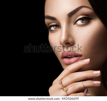 Beautiful woman face portrait isolated on black background. Sexy lips with fashion natural beige matte lipstick makeup, beige nails, trendy midi rings on her fingers. Closeup