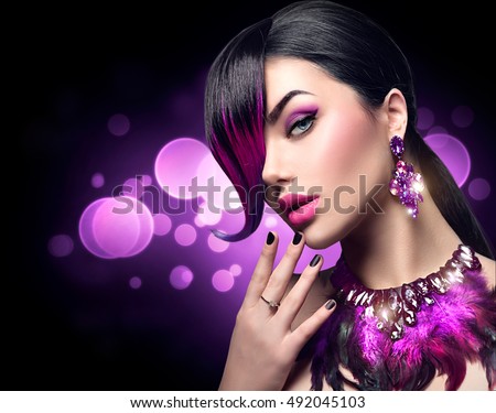 Sexy Beautiful fashion woman with purple dyed hair fringe hairstyle and violet color accessories, necklace and earrings with crystals. Beauty model girl portrait isolated on black background.