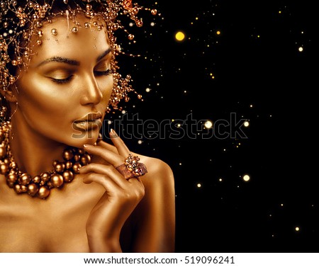 Beauty Fashion model girl with Golden Makeup, Gold skin make up, hair and jewellery on black background. Gold earrings, ring and necklace. Metallic, glance Fashion art portrait, Hairstyle and make up