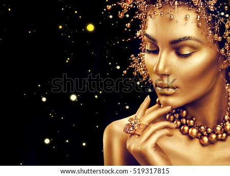 Gold Woman skin. Beauty fashion model girl with Golden make up, hair and jewellery on black background. Gold earrings, ring and necklace. Metallic, glance Fashion art portrait, Hairstyle and make up