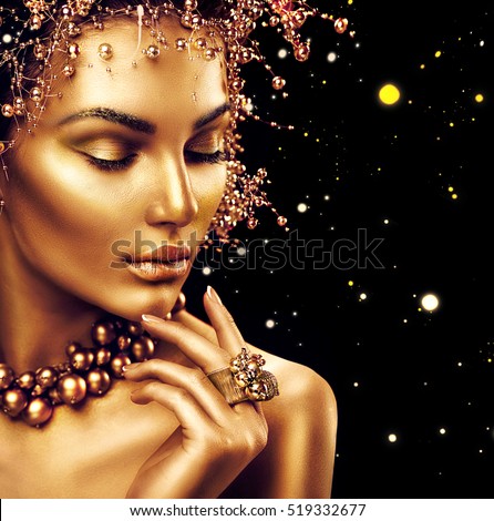 Beauty Fashion model girl with Golden Makeup, Gold skin makeup, hair and jewellery on black background. Gold earrings, ring and necklace. Metallic, glance Fashion art portrait, Hairstyle, make up