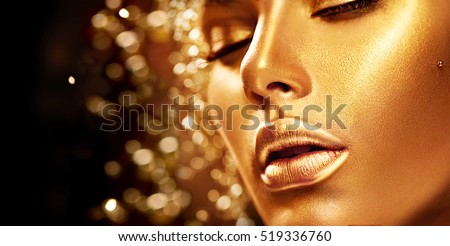 Fashion art Golden skin Woman face portrait closeup. Beauty gold eyes, Lips and Skin. Model girl. Glamour shiny professional makeup