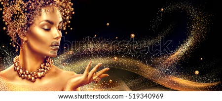 Gold Woman skin. Beauty fashion model girl with Golden make up, hair and jewellery on black background. Gold earrings, ring and necklace. Metallic, glance Fashion art portrait, Hairstyle and make up