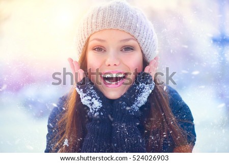 Winter young woman portrait. Beauty Joyful  Model Girl touching her face skin and laughing, having fun in winter park. Beautiful young woman laughing outdoors. Enjoying nature, wintertime