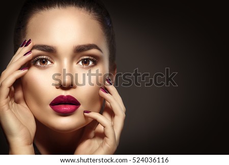 Beauty Brunette Woman with Perfect Makeup. Beautiful Professional Holiday Make-up. Red Lips and Nails, perfect eyebrows. Beauty Girl's Face isolated on dark background