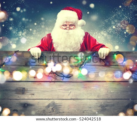 Happy Santa Claus holding blank advertisement wooden banner background with copy space. Smiling Santa Claus pointing in old wood blank sign. Christmas theme, sales, advertising