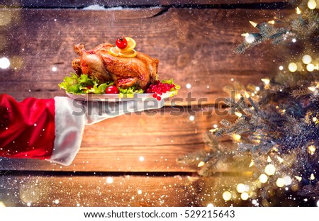Christmas Holiday dinner. Santa Claus hand holding roasted Chicken. Christmas and New Year food concept, over rural wooden background.