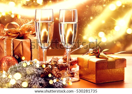Christmas and New Year Celebration. Two Champagne Glasses and Gifts over Golden Blinking Holiday Background. Christmas party, Winter Holiday party, Xmas  decoration.