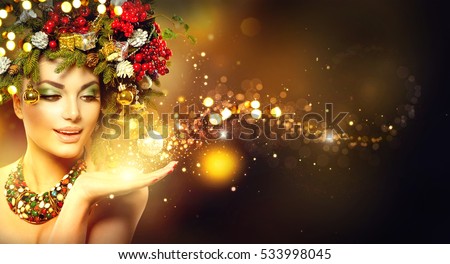 Christmas Wish. Winter Woman with Miracle in Her Hand. Fairy. Beautiful New Year and Christmas Tree Holiday Hairstyle and Makeup. Gift. Magic Girl. Beauty Fashion Model over Holiday Blurred Background