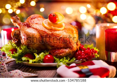 Christmas Dinner. Roasted chicken. Winter Holiday table served, decorated with candles. Roast turkey over wooden background with christmas tree, table setting.