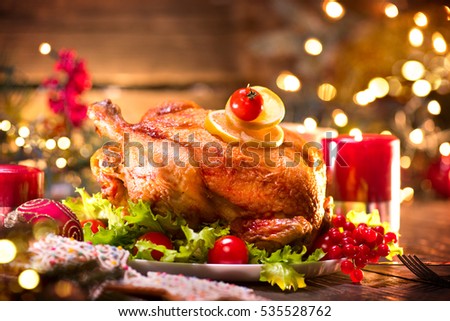 Christmas Dinner. Roasted chicken. Winter Holiday table served, decorated with candles. Roast turkey over wooden background with christmas tree, table setting.