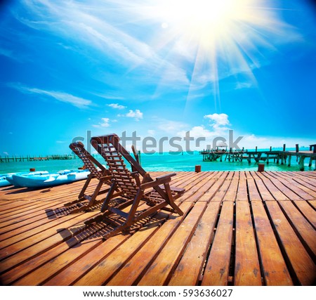 Exotic Beach, Paradise. Travel, Tourism and Vacations Concept. Landscape of Tropical Resort. couple of sun beds waiting for tourists. Jetty near Cancun, Mexico