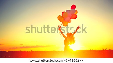 Beauty girl running and jumping on summer field with colorful air balloons over Sunset clear sky. Silhouette, Happy young healthy woman enjoying nature outdoors. Running and jumping female. Flying