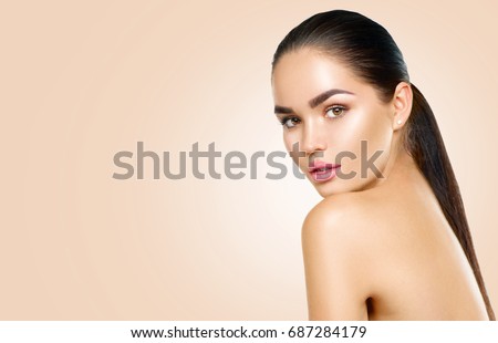 Beauty Woman Face closeup. Beautiful brunette young spa model girl with perfect skin. Spa, Skincare and body care concept. Fresh Clean Skin. Portrait of female looking at camera. Beige background