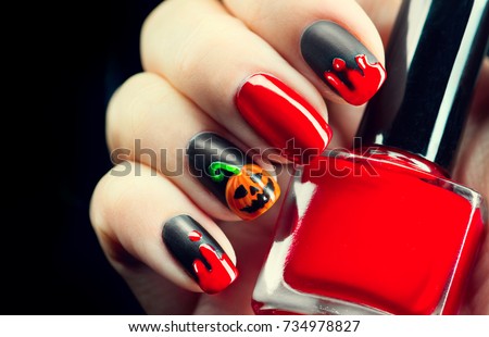 Halloween manicure design ideas. Halloween Nail art design. Nail Polish. Beauty Trendy Stylish Colorful Nails and Nailpolish. Black matte nailpolish with blood drips and pumpkin. Isolated on black.