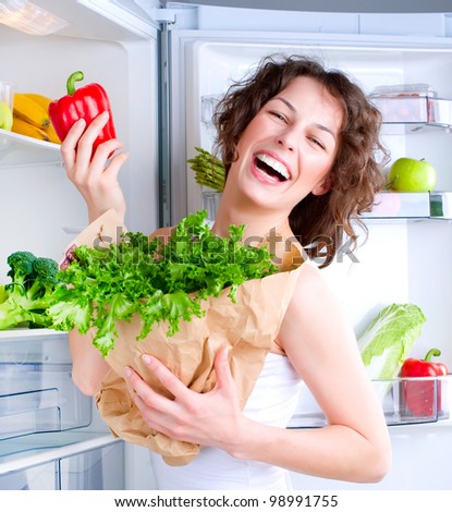Dieting concept .Diet. Beautiful Young Woman near the Refrigerator with healthy food. Fruits and Vegetables