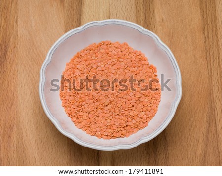 Red lentils Petite crimson lentils in a bowl on a wooden background from above