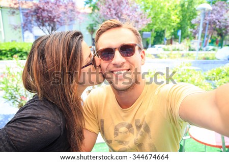 Couple in love are sitting in bar and take a selfie memory picture. Lovers are chilling and drinking a coffee in a sunny day after shopping day in the city. Image of smiling young joyful best friends