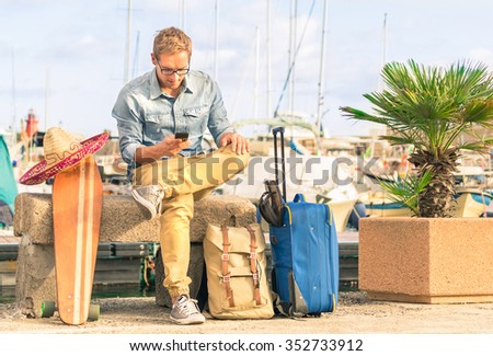 Young hipster man ready for the next destination vacation holding his smartphone. Modern concept of freedom and alternative lifestyle - Cheap travel backpacking around the world