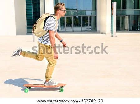 Hipster men going to  study in city with an alternative and ecologic way. Concept of carefree youth and freedom outdoors against city background. Active guy enjoying everyday life moments doing sport