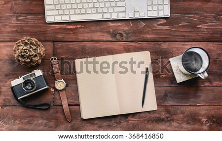Work space on wood table of a creative designer or photographer with laptop, sketchbook, coffee and other objects of inspiration. Stylish home studio concept of technology trends. Vintage filter look