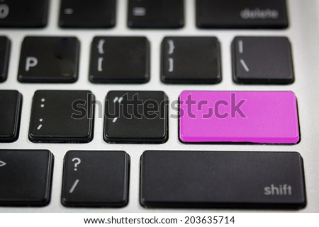 Close up of a black keyboard with a button in pink